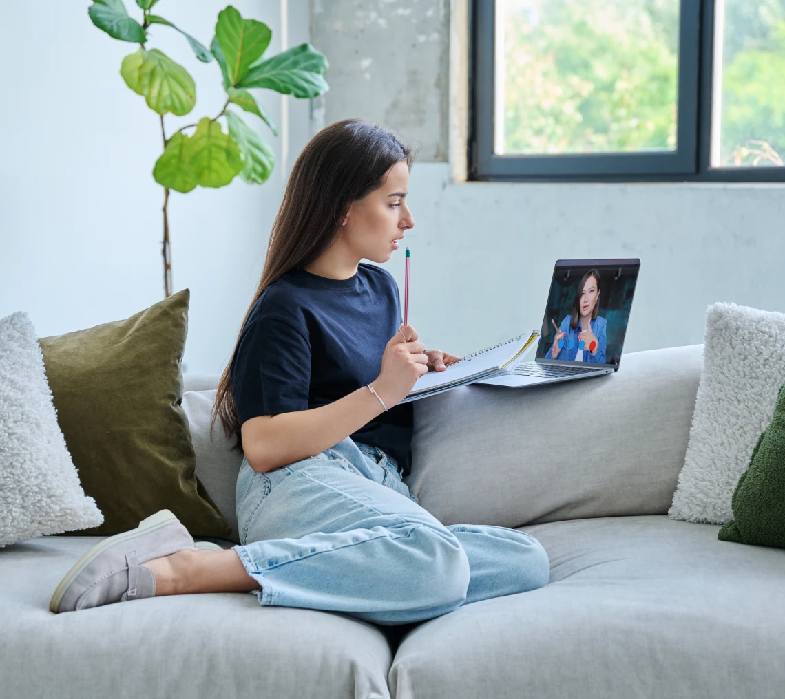 Woman studying on couch with laptop.