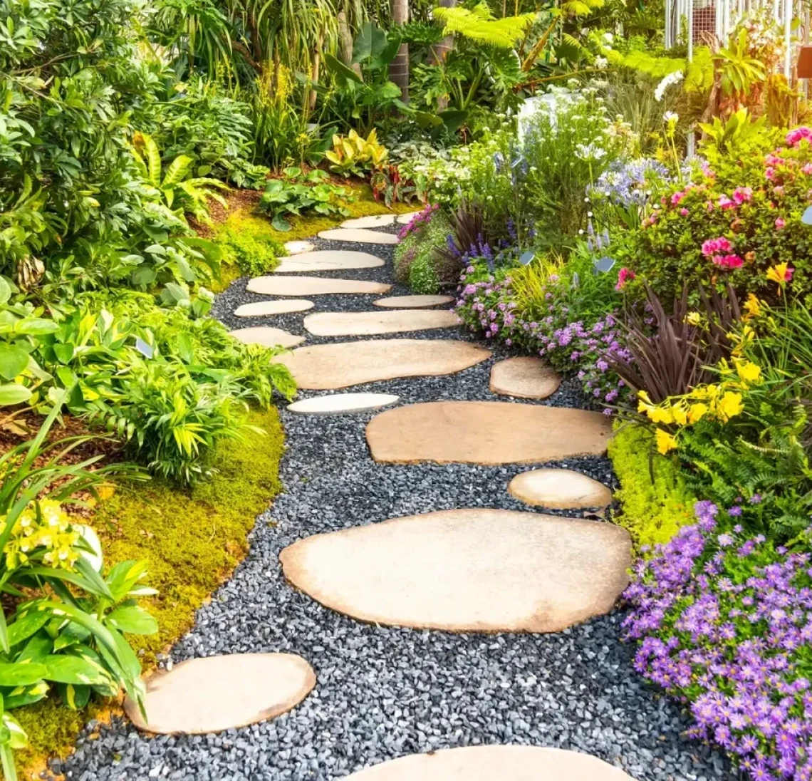 Stone path through lush, colorful garden.