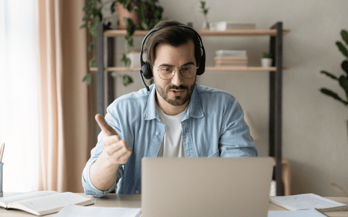 Man wearing headphones using laptop for video call.